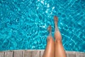 Beautiful women legs in blue water. Beautiful sexy female feet relaxing by the swimming pool. Summer background for traveling Royalty Free Stock Photo