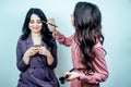 Beautiful woman make-up artist visagiste applying cosmetics make-up on face of female client in studio beauty salon . Royalty Free Stock Photo