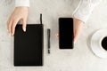 Beautiful women`s hands with up-to-date smartphone, notebook, fountain pen and cup of coffee on concrete background Royalty Free Stock Photo