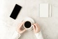 Beautiful women`s hands with up-to-date smartphone, opened notepad, pen and cup of coffee on marble background. Women`s Royalty Free Stock Photo