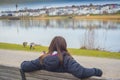 A beautiful women sits on the beanch near a lake and admire the wonderful scenery