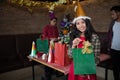 Beautiful woman wear red dress and santa claus hat showing green gift bag on hand in restaurant. Royalty Free Stock Photo