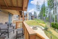 Beautiful wooden back porch with chairs on the hill and large backyard patio with fire pit and pine trees