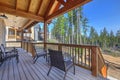 Beautiful wooden back porch with chairs on the hill and large backyard patio with fire pit and pine trees Royalty Free Stock Photo