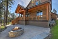 Beautiful wooden back porch with chairs on the hill and large backyard patio with fire pit and pine trees