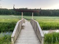 Beautiful wooden bridge with a boat figure leading across a lush marshy landscape in Stockholm Royalty Free Stock Photo