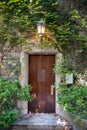 Beautiful wooden door covered by green ivy with vintage lighted lantern