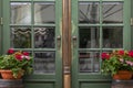 Beautiful wooden door of green color in an old city. On both sides of the entrance there are pots of flowers. Elegant vintage fron Royalty Free Stock Photo