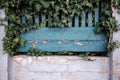 Beautiful wooden fence with peeling blue paint with a concrete cracked base and green plants. Provincial town Royalty Free Stock Photo