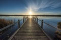 Beautiful wooden pier by the calm ocean with the beautiful sunset over the horizon Royalty Free Stock Photo