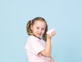 Beautiful 8 year old girl is playing with pink slime in front of blue background