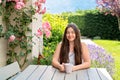 Beautiful 40 years old woman sitting on terrace in blooming summer garden enjoying tea. Royalty Free Stock Photo