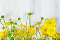 Beautiful yellow Buttercup bouquet lying on white wooden boards.