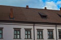 Beautiful yellow historical medieval European low-rise buildings with a red tile roof gable and rectangular windows with bars