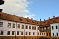 Beautiful yellow historical medieval European low-rise buildings with a red tile roof gable and rectangular windows with bars