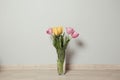 Beautiful yellow and pink tulips in glass vase on the floor in the room Royalty Free Stock Photo