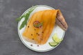 Beautiful yellow smoked haddock fish fillet on a plate with a branch of fresh arugula, lime and pink berry on grey slate