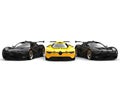 Beautiful yellow super car stands out between two black sports cars Royalty Free Stock Photo