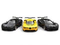 Beautiful yellow super car with two black sports cars on each side Royalty Free Stock Photo