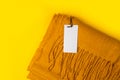 Beautiful yellow warm winter scarf with label tag mockup template on yellow background with space for text, top view Royalty Free Stock Photo