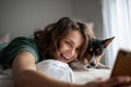 Beautiful young adult cheerful woman taking selfie on smartphone with her dog bassengi in the morning in bed Royalty Free Stock Photo