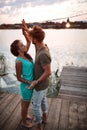 Young adult couple dancing at wooden platform by the river at sunset