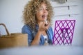 Beautiful young adult woman portrait using lipstick and make up her face checking on the mirror at home sittong on the table - Royalty Free Stock Photo