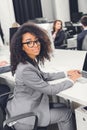 Beautiful young african american businesswoman in eyeglasses smiling at camera while sitting Royalty Free Stock Photo