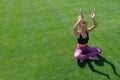 A beautiful young African-American girl in a black T-shirt and pink sneakers is engaged in yoga on the green grass and Royalty Free Stock Photo