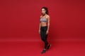 Beautiful young african american sports fitness woman in sportswear posing working out isolated on bright red background Royalty Free Stock Photo