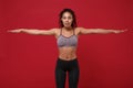Beautiful young african american sports fitness woman in sportswear posing working out isolated on red background in Royalty Free Stock Photo
