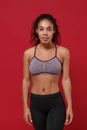 Beautiful young african american sports fitness woman in sportswear posing working out isolated on red wall background Royalty Free Stock Photo