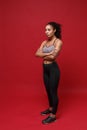 Beautiful young african american sports fitness woman in sportswear posing working out isolated on red wall background Royalty Free Stock Photo