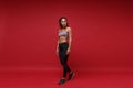 Beautiful young african american sports fitness woman in sportswear posing working out isolated on red wall background Royalty Free Stock Photo