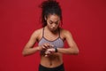 Beautiful young african american sports fitness woman in sportswear working out isolated on red background in studio Royalty Free Stock Photo