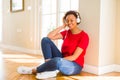 Beautiful young african american woman with afro hair listening to music and dancing wearing headphones Royalty Free Stock Photo