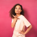 Beautiful young African American woman with Afro hair sending air kisses, looking positively at camera wearing peachy t Royalty Free Stock Photo