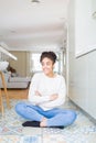 Beautiful young african american woman with afro hair sitting on the floor smiling looking side and staring away thinking Royalty Free Stock Photo