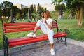 Beautiful young African American woman with afro hairstyle wearing white dress. Beautiful Girl sitting in the park with a Royalty Free Stock Photo