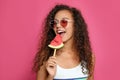 Beautiful young African American woman eating watermelon on crimson background