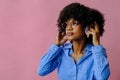 beautiful young African american woman listening music in headphones  on pink background Royalty Free Stock Photo