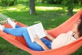 Beautiful young African-American woman reading book in hammock outdoors Royalty Free Stock Photo