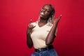 Beautiful young african american woman shouting with crazy expression doing rock symbol with hands up over red isolated background Royalty Free Stock Photo