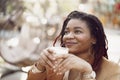 Beautiful young african american woman sitting in outdoor cafe and drinking coffee Royalty Free Stock Photo