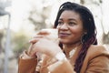Beautiful young african american woman sitting in outdoor cafe and drinking coffee Royalty Free Stock Photo