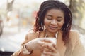 Beautiful young african american woman sitting in outdoor cafe and drinking coffee Royalty Free Stock Photo