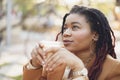 Beautiful young african american woman sitting in outdoor cafe and drinking coffee Royalty Free Stock Photo