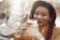 Beautiful young african american woman sitting in outdoor cafe and drinking coffee Royalty Free Stock Photo