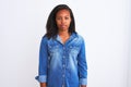 Beautiful young african american woman wearing denim jacket over isolated background Relaxed with serious expression on face Royalty Free Stock Photo