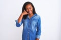 Beautiful young african american woman wearing denim jacket over isolated background smiling doing phone gesture with hand and Royalty Free Stock Photo